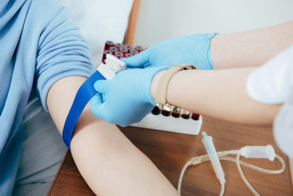 partial view of doctor using tourniquet for blood test in hospital